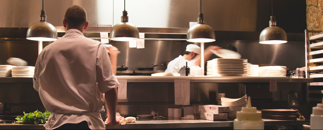 A server waits as a chef preps food in the kitchen